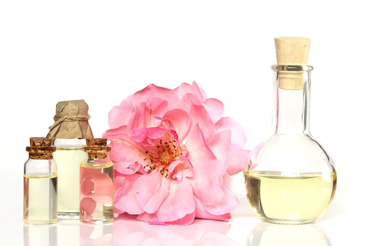 natural pure rose oil. essential rose oil set in glass bottles with and  large pink rose on a white background. Organic Natural Oil